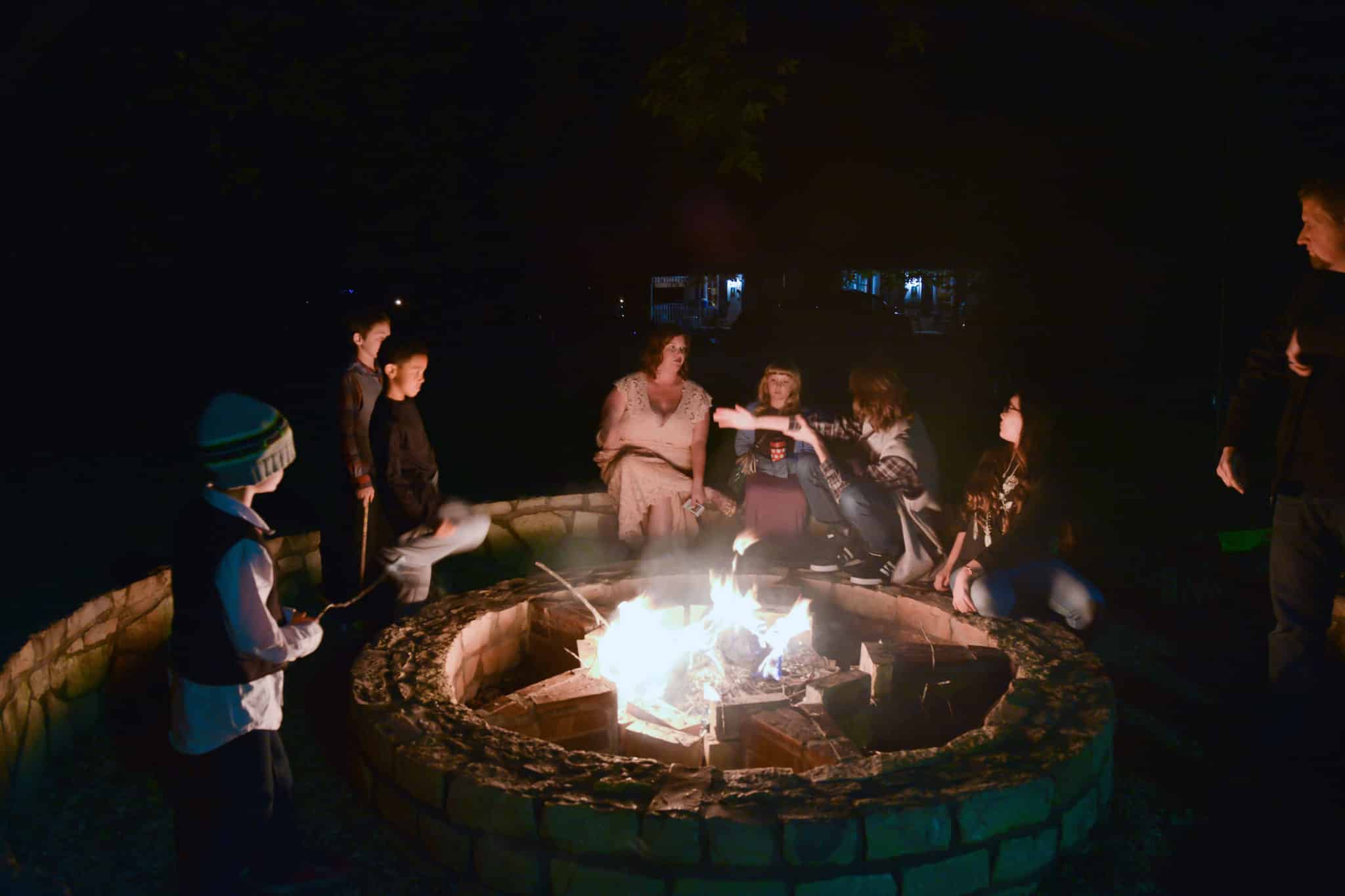 A family roasts marshmallows around a campfire at night