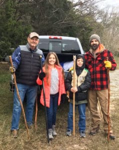 Family of 4 stands with walking sticks in winter apparel