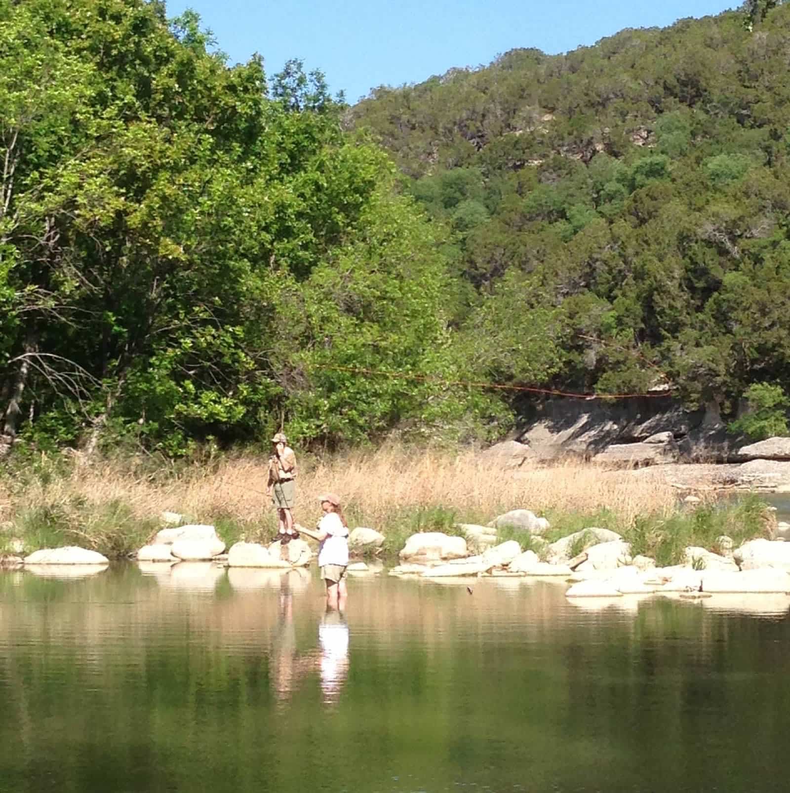 A man and woman stand in a river fly fishing