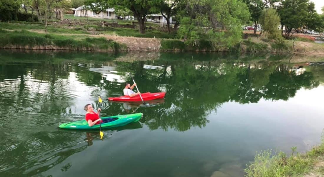 A man and a woman in red and green kayaks going down the river.