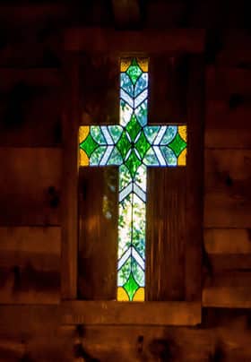 Stained glass cross surrounded by wood siding