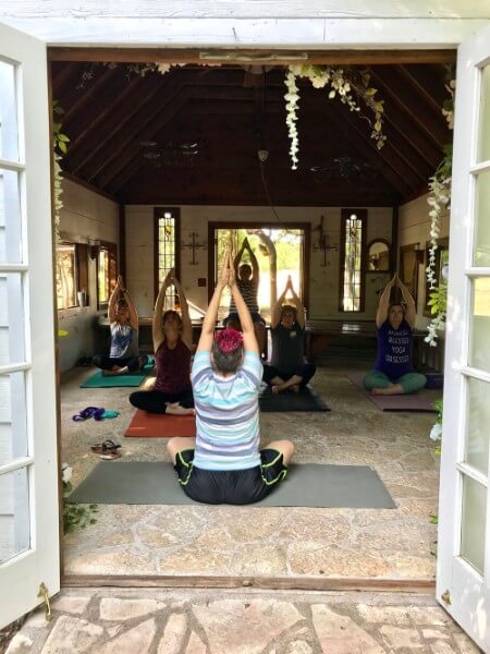 A group of people practice yoga in a rustic space. 