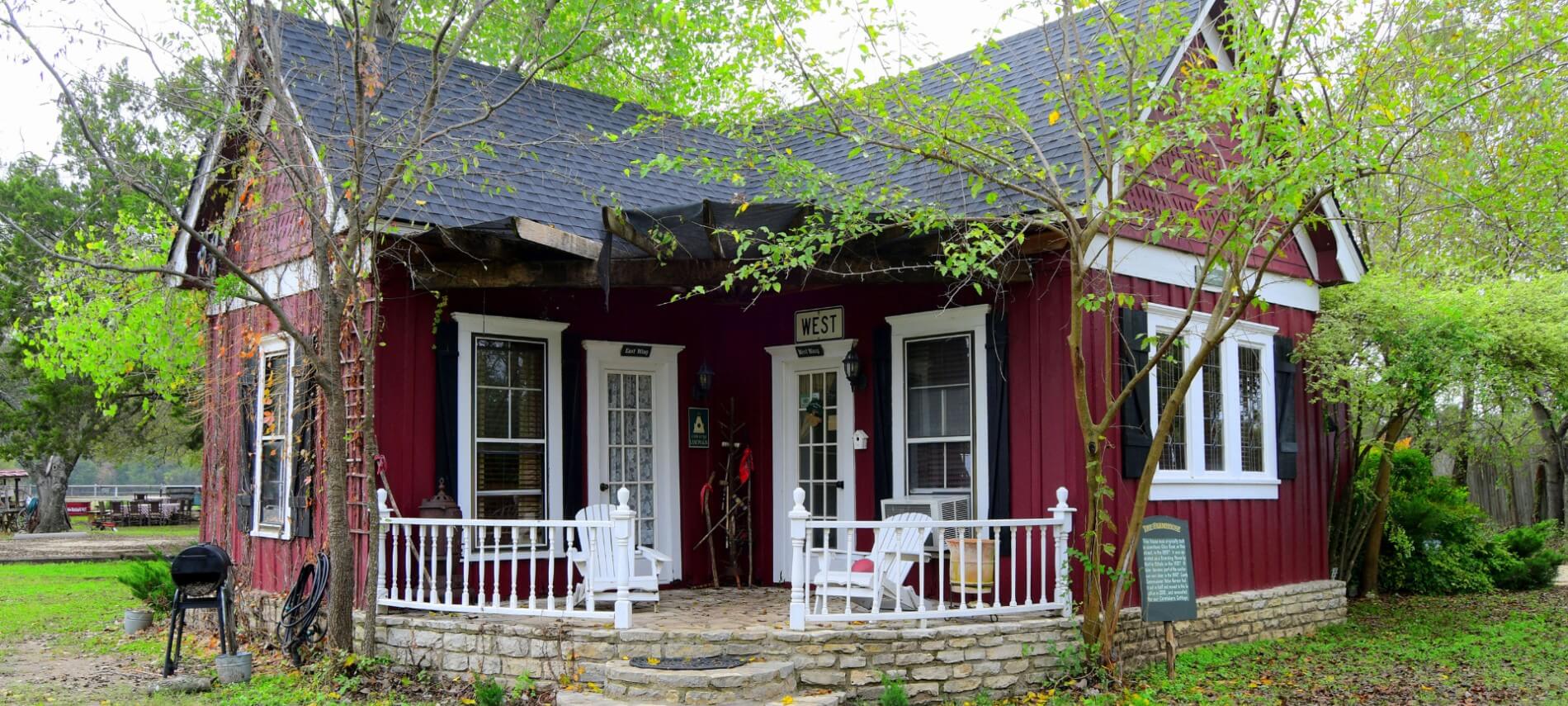 Cute red cabin with black roof and shutters with a stone porch.